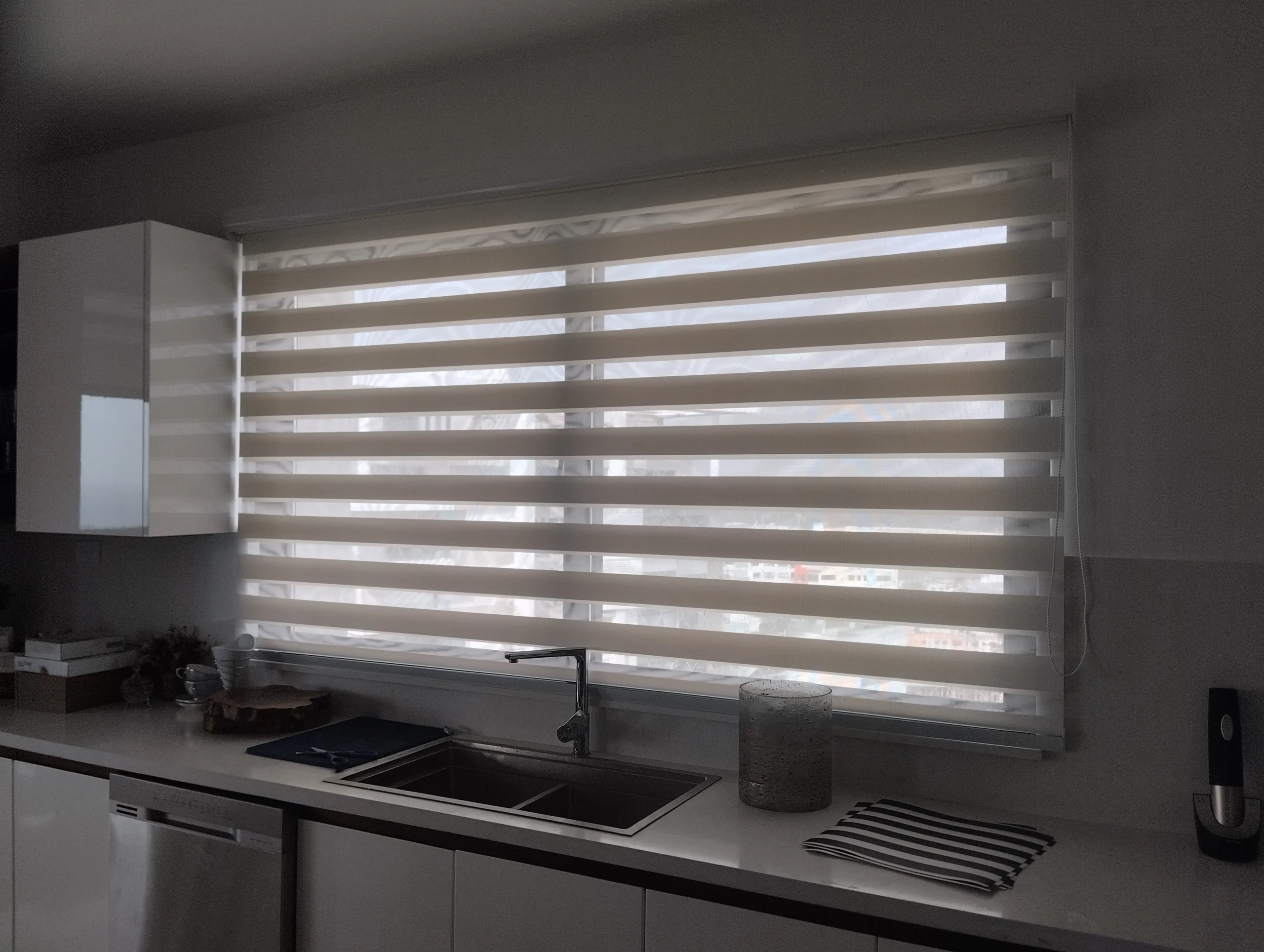Cortina Zebra con tela PVC instalada en una ventana sobre el fregadero de una cocina