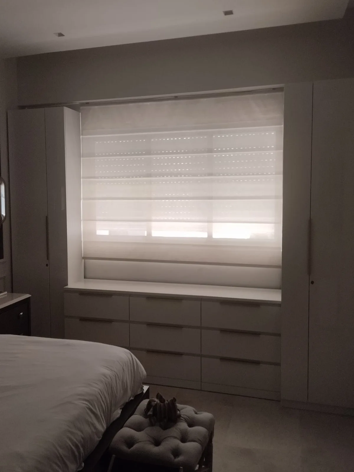 Habitacion con cortina romana screen instalado entre muebles empotrados