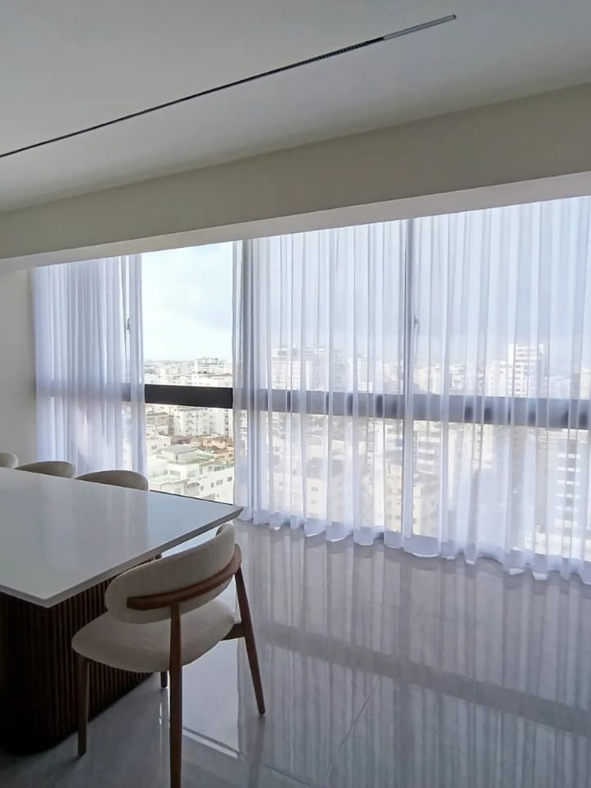 Instalación de cortinas de riel hotelero con visillo en comedor con vista a la ciudad de Santo Domingo