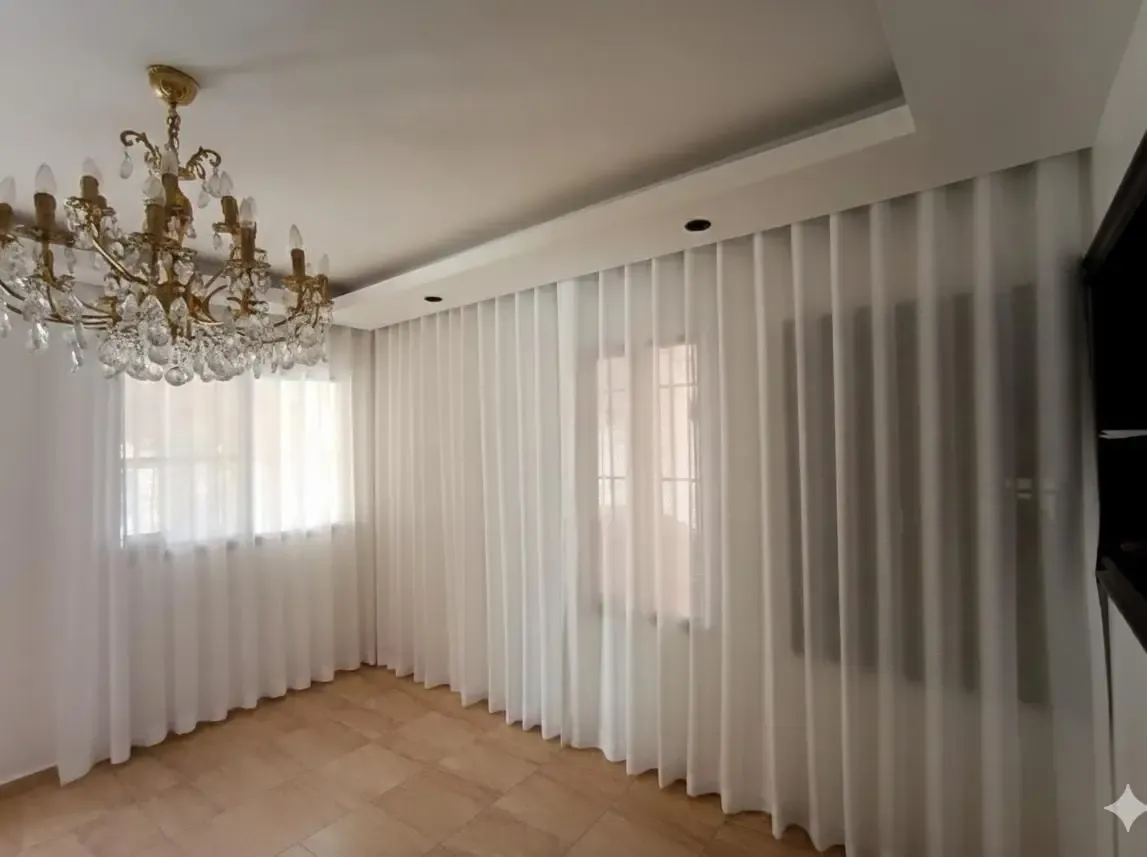 Cortinas de ondas perfectas blancas instaladas por Blinds Company en una sala esquinera en Santo Domingo