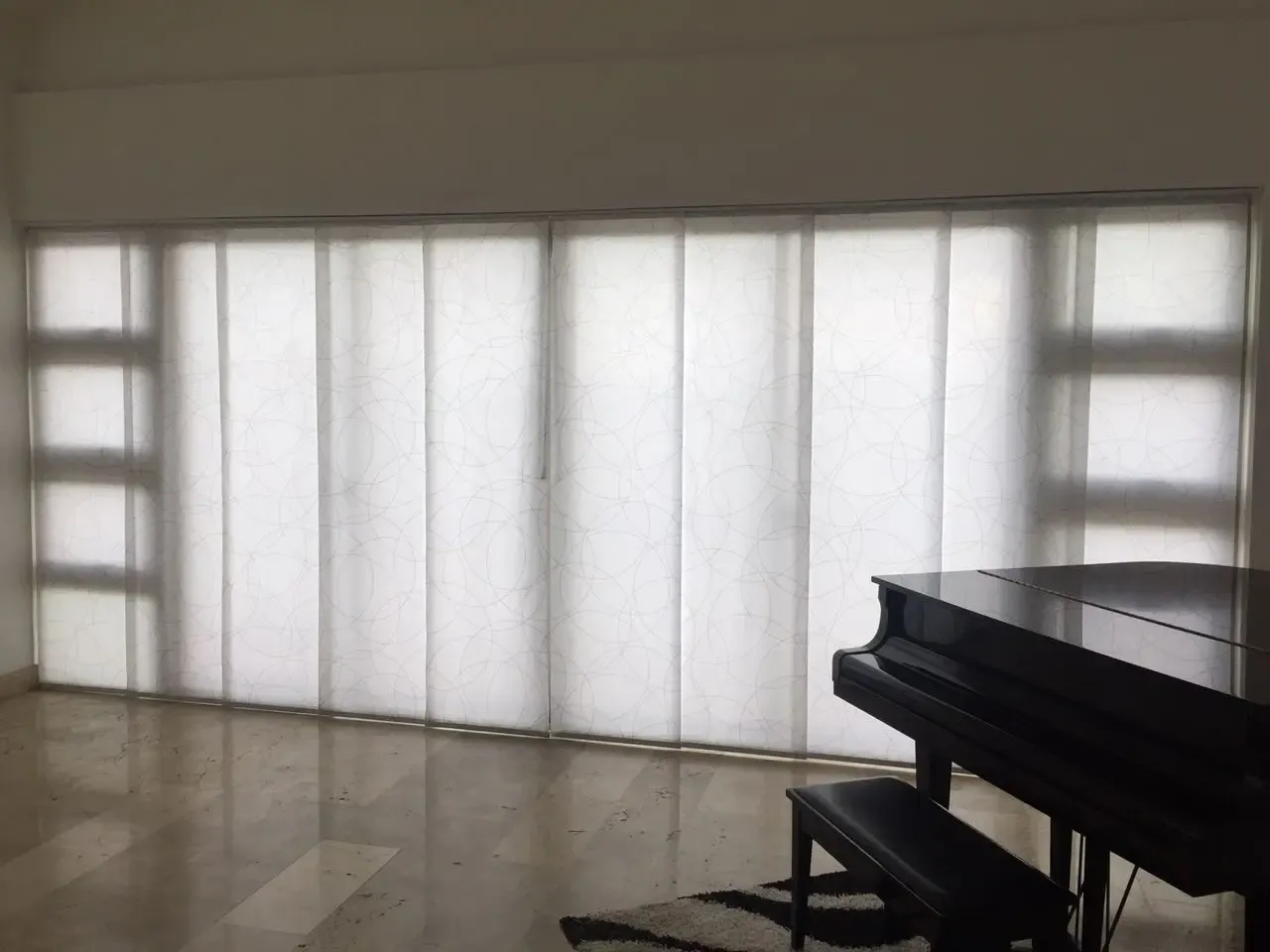 Panel deslizante instalado por Blinds Company en sala con piano en República Dominicana