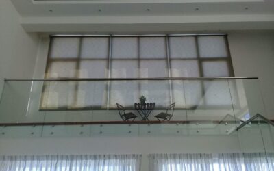 Cortinas Enrollables Traslúcidas con motor instaladas en ventanal de doble altura en una sala