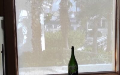 Persiana con tela Traslúcida color Blanco instalado en ventanal detrás de una botella en un mostrador